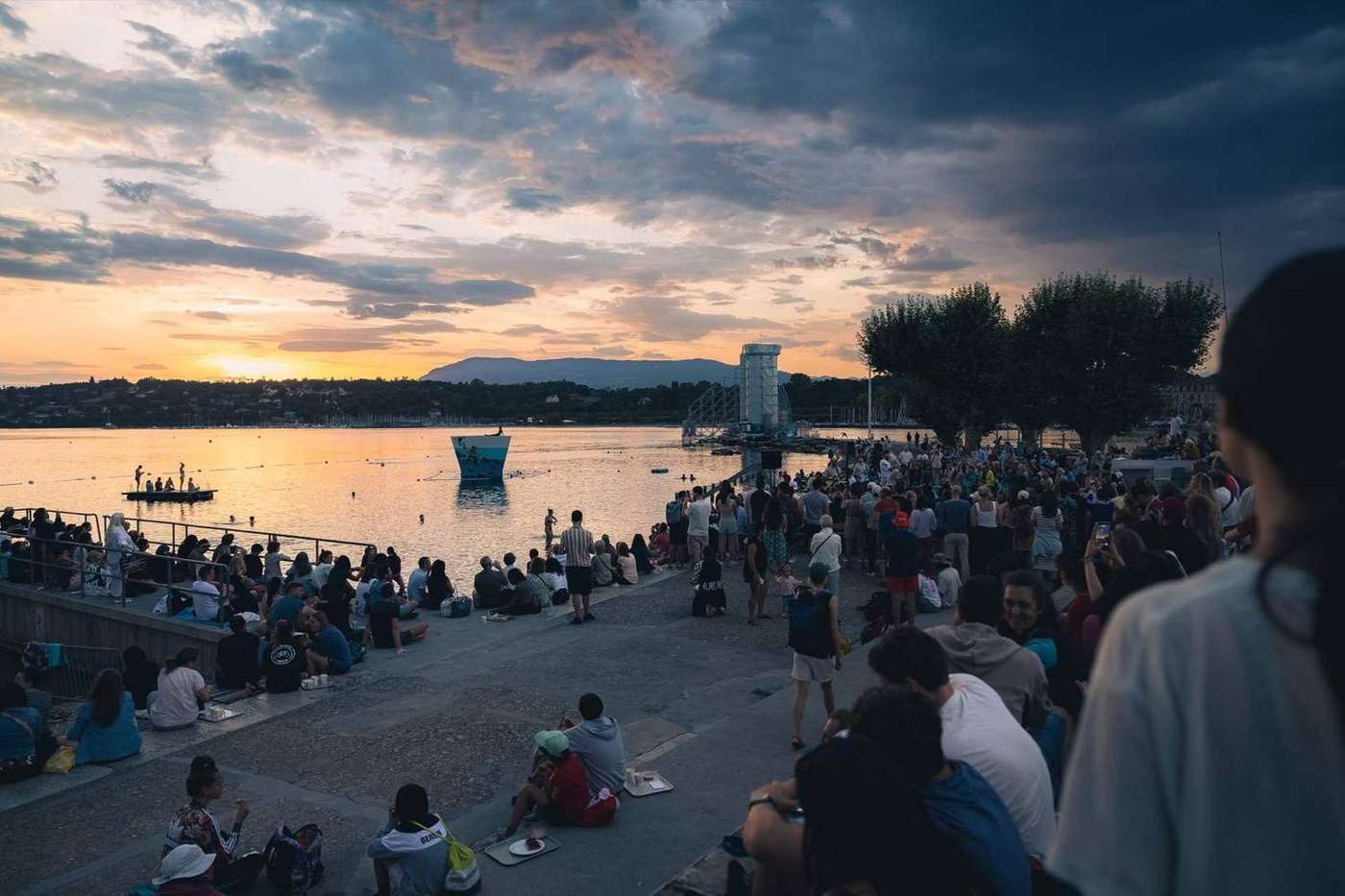 Public réuni au bord du lac au crépuscule